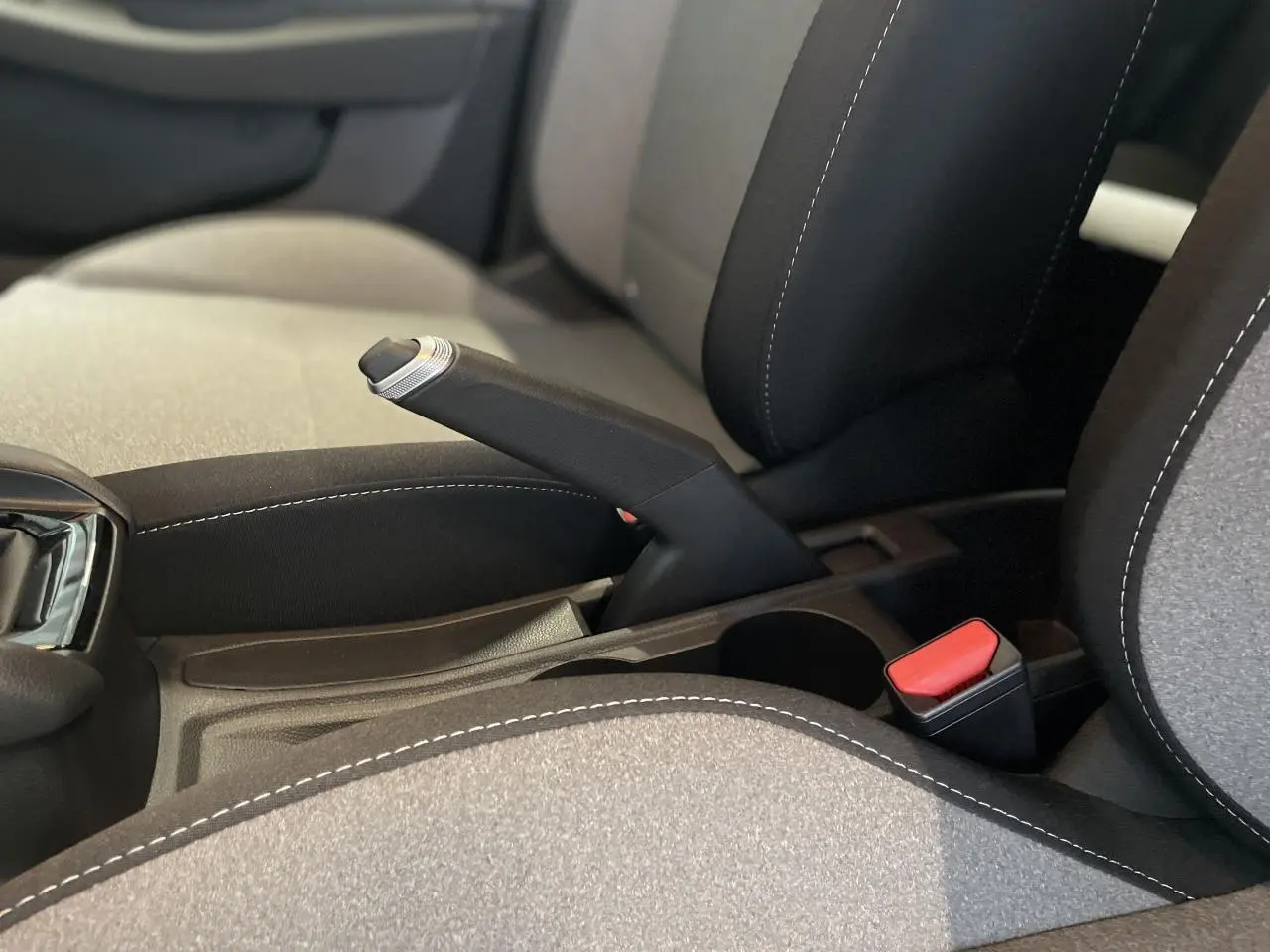 Gros plan sur le frein à main manuel et la sellerie tissu gris avec surpiqûres blanches de la Renault Clio 2025.