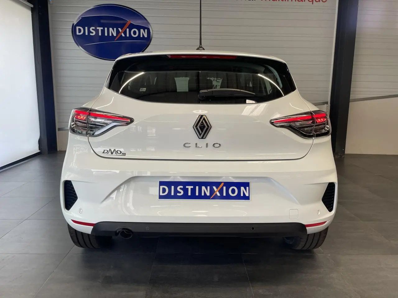 Vue arrière d'une Renault Clio blanche 2025 avec feux LED et logo distinctif dans un showroom.