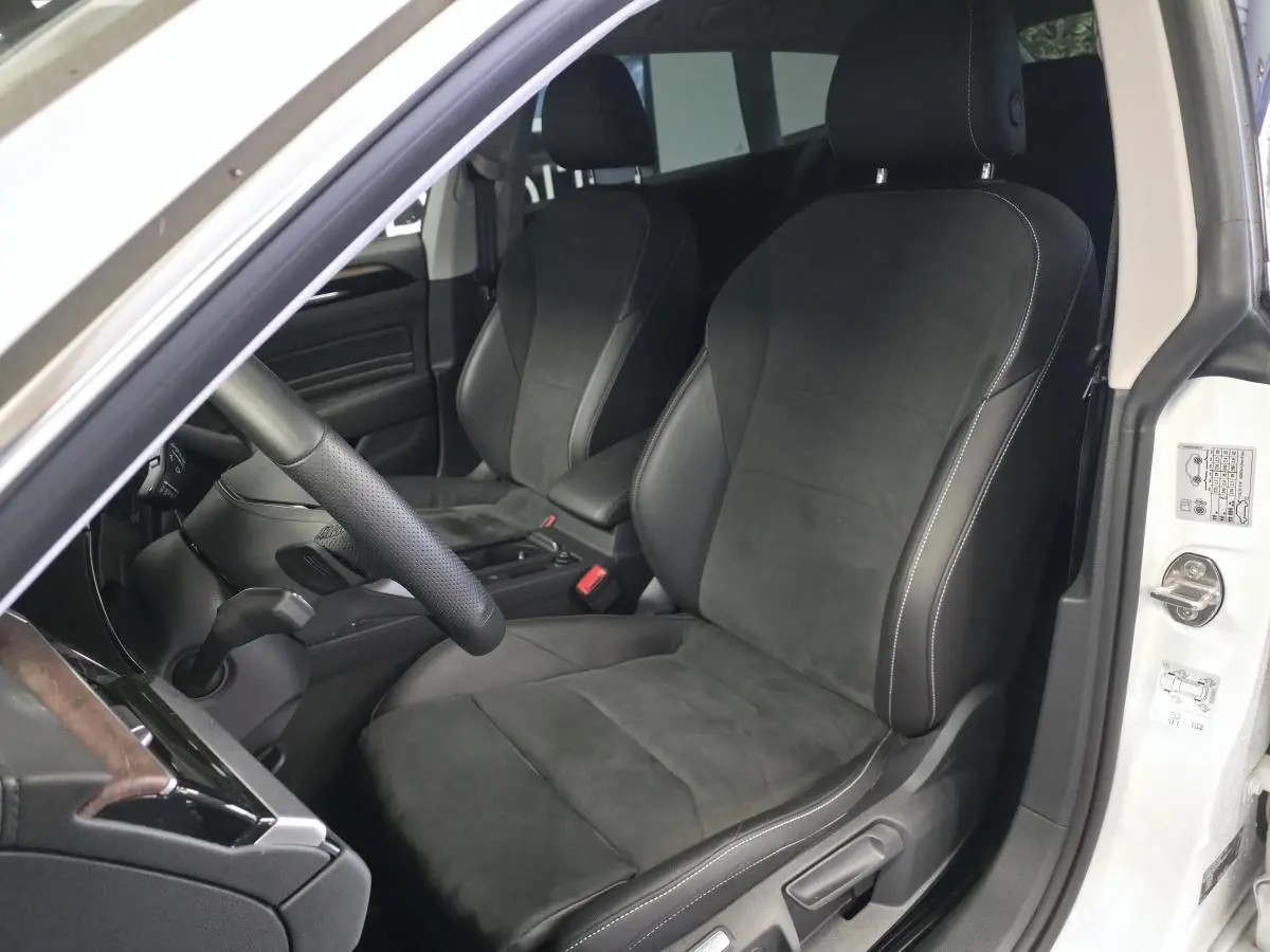 Vue intérieure côté conducteur de la Volkswagen Arteon Elegance blanche avec sièges avant en microfibre noire et coutures contrastées.