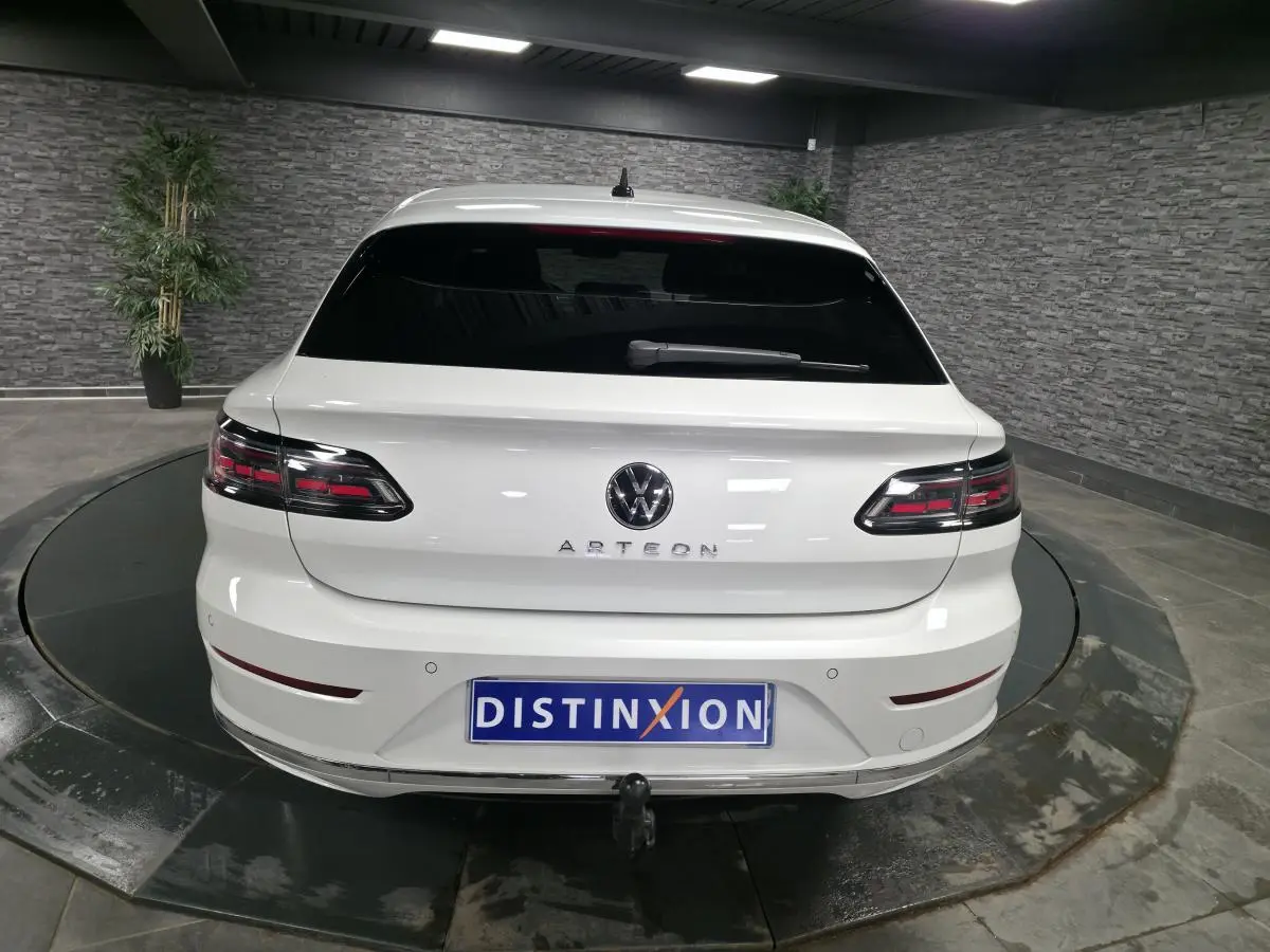 Vue arrière d'une Volkswagen Arteon blanche avec feux LED sombres et attelage rabattable électrique visible.