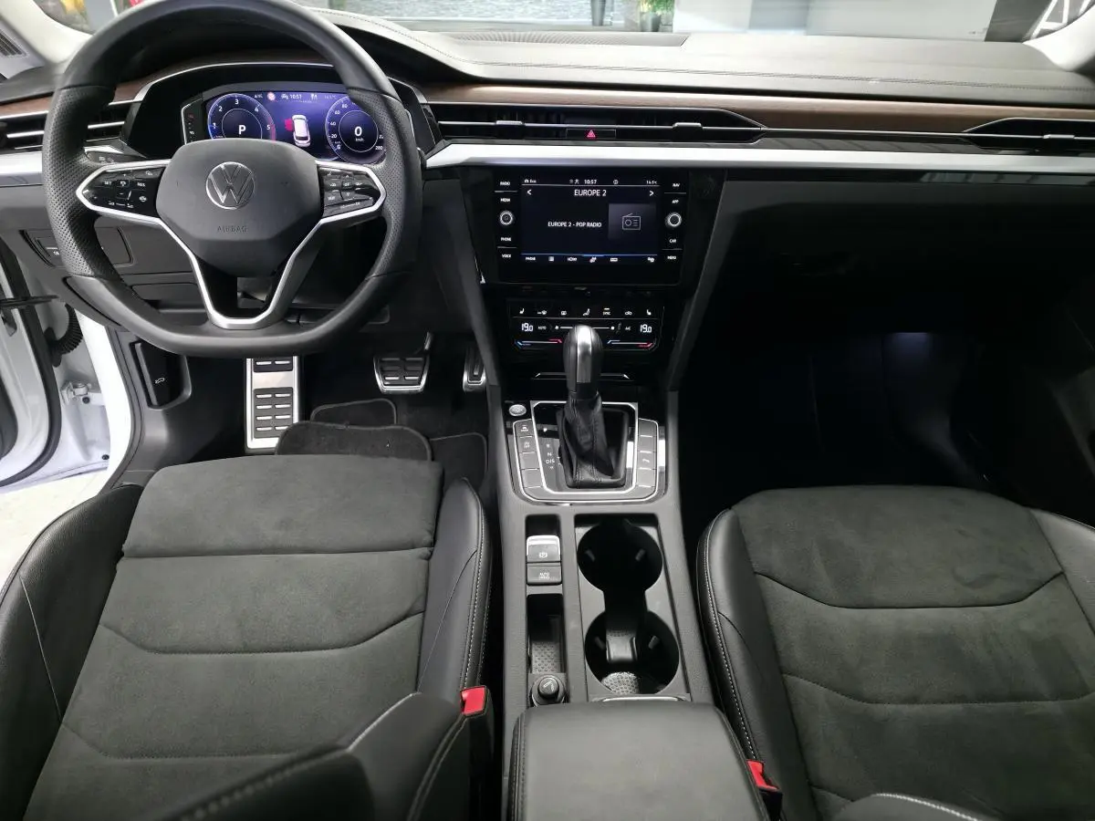 Intérieur avant de la Volkswagen Arteon 2024, vue centrée sur le tableau de bord et la console avec sellerie noire et volant multifonction.