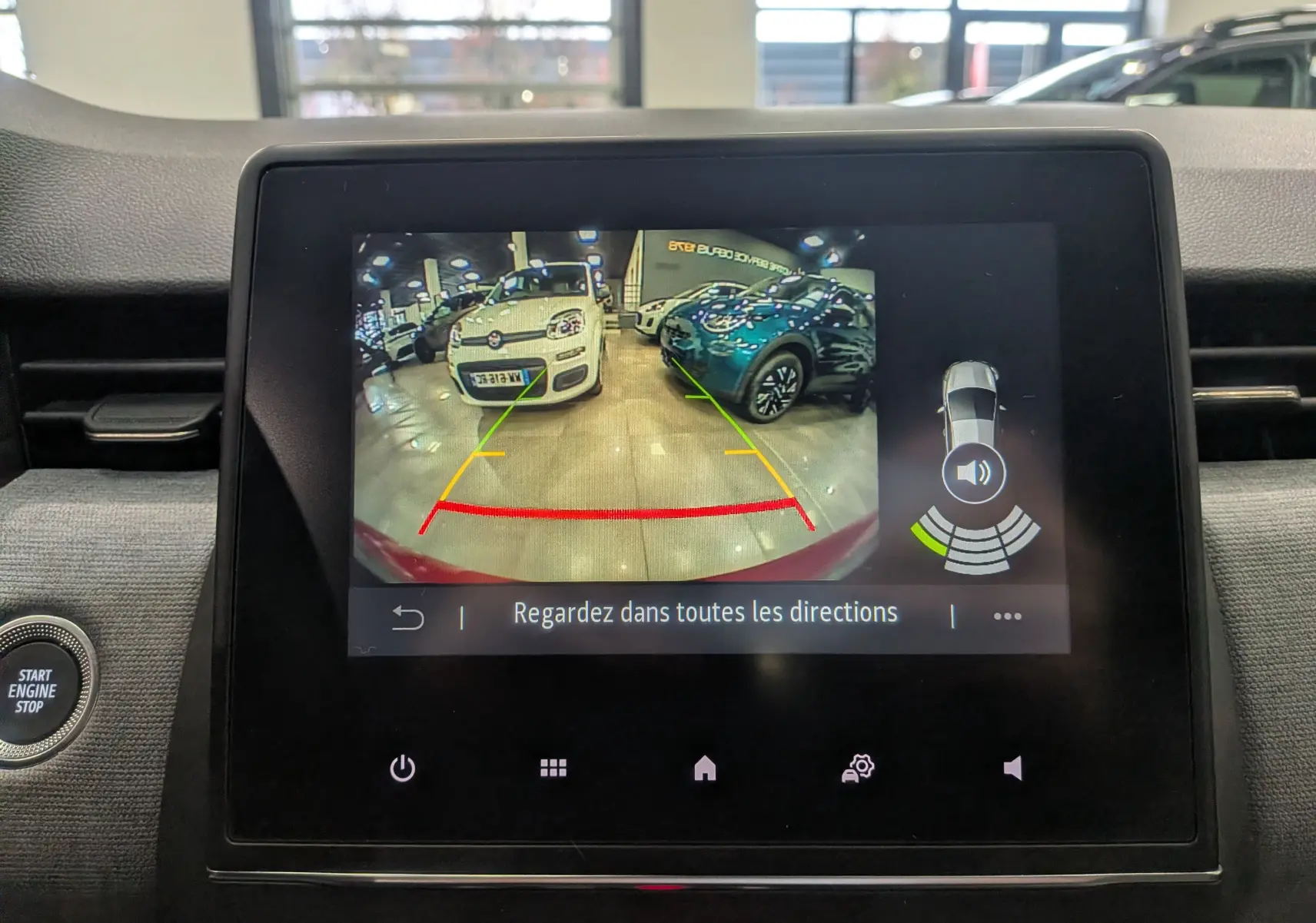 Écran de caméra de recul affichant l’arrière du Renault Clio V Rouge Flamme en intérieur avec guidage de trajectoire.