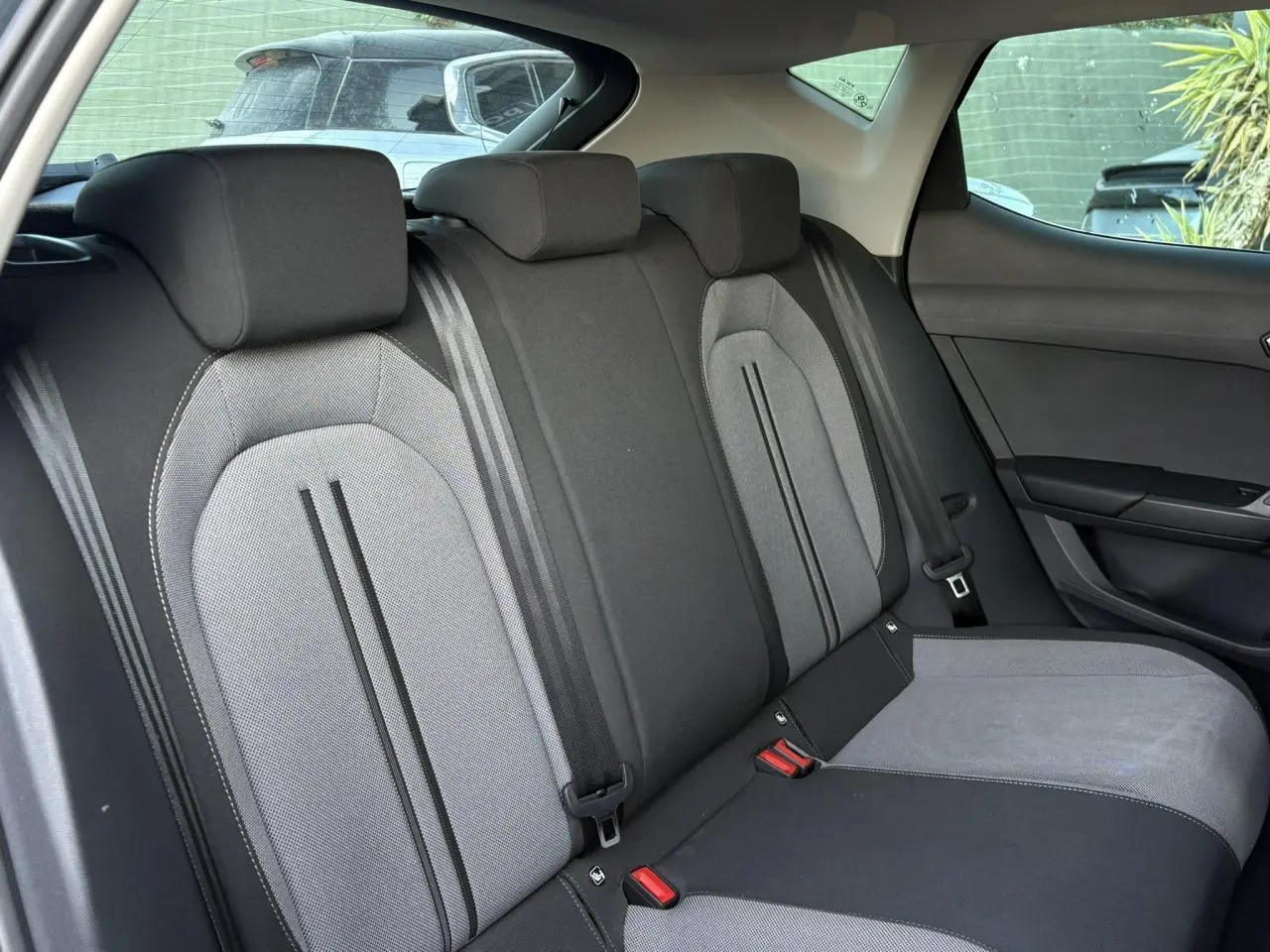 Vue latérale droite des sièges arrière gris et noirs du SEAT LEON 1.5 eTSI 115 DSG Style 2025, intérieur spacieux et moderne.
