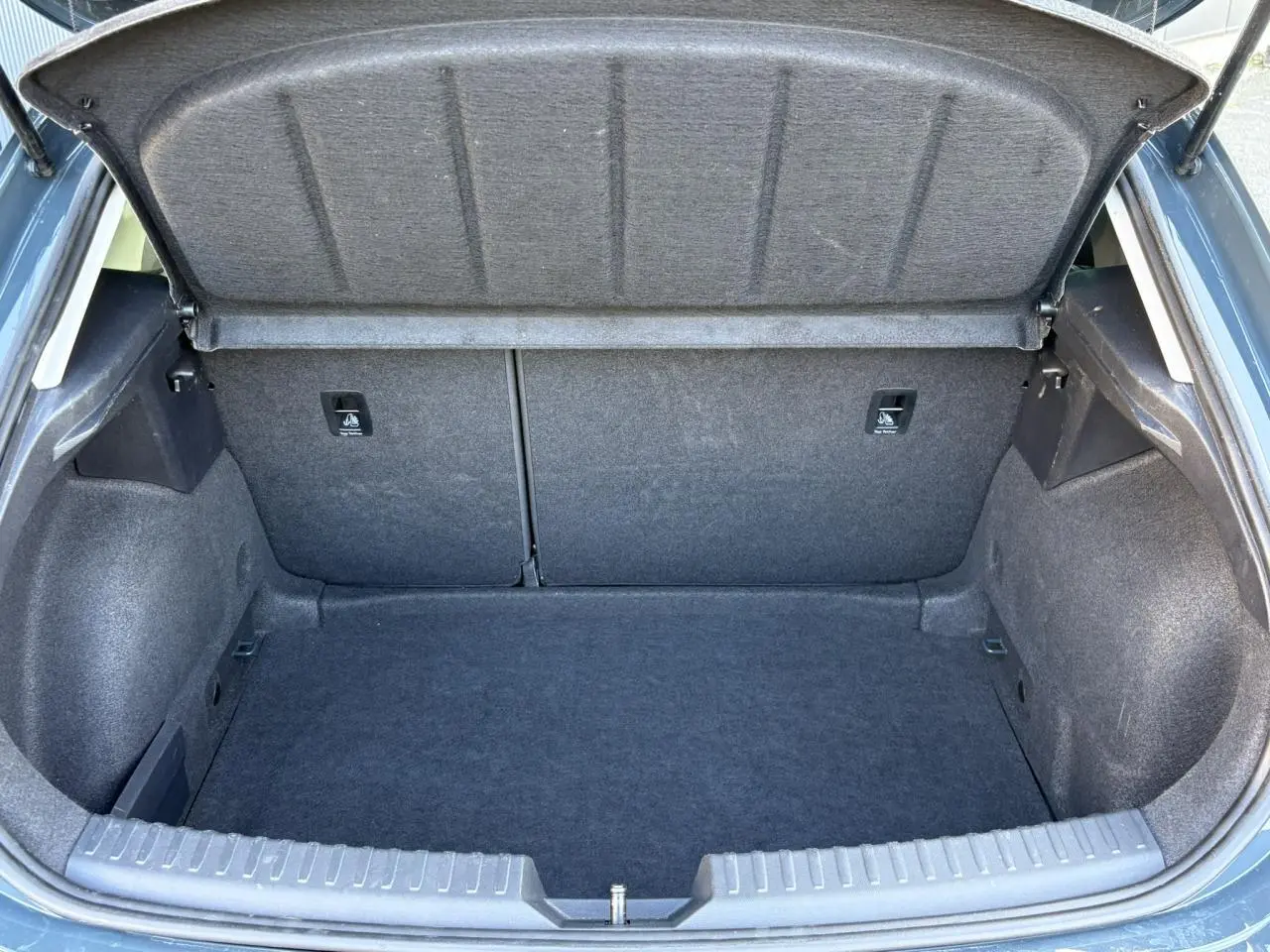 Coffre ouvert vu de l'arrière d'une SEAT LEON 1.5 eTSI 115 DSG Style 2025 en Bleu Fjord, intérieur gris.