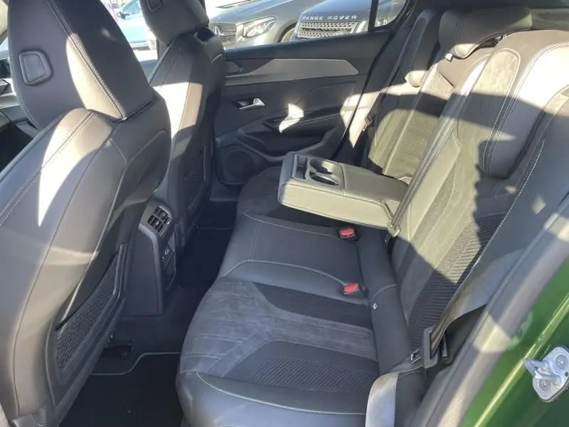Vue intérieure arrière droite de la Peugeot 308 1.5 HDI 130 GT PACK 2022 en vert olivine, avec accoudoir central déployé.