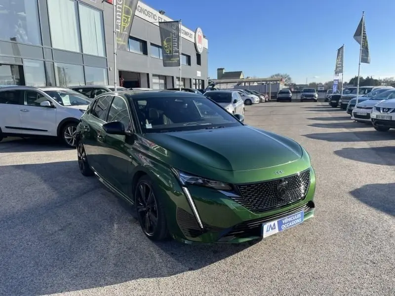 Peugeot 308 1.5 HDI GT Pack 2022 en vert olivine, vue 3/4 avant avec calandre noire et jantes foncées.