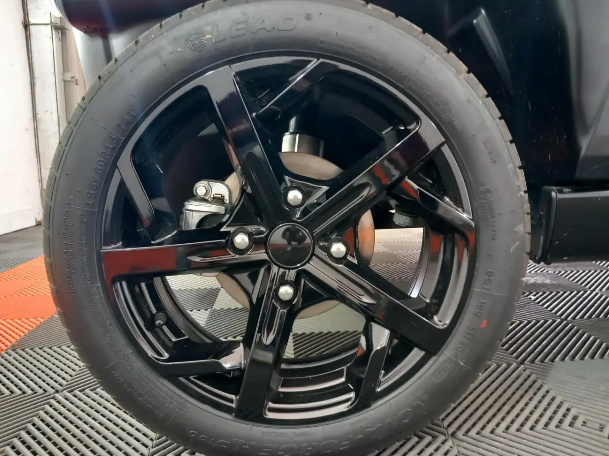 Gros plan sur la roue avant droite avec jante noire brillante du véhicule bleu Aixam MEGA E-Scouty Evo 2026.