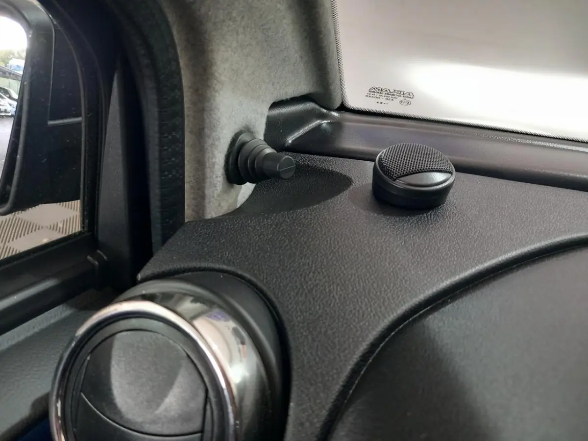 Détail intérieur côté conducteur montrant la commande de ventilation et le bouton de verrouillage sur tableau de bord noir.