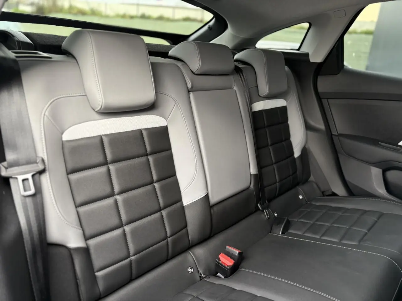 Vue intérieure de la banquette arrière bicolore gris clair et noir avec appuie-têtes et ceintures visibles sur Citroën C4 Hybrid.