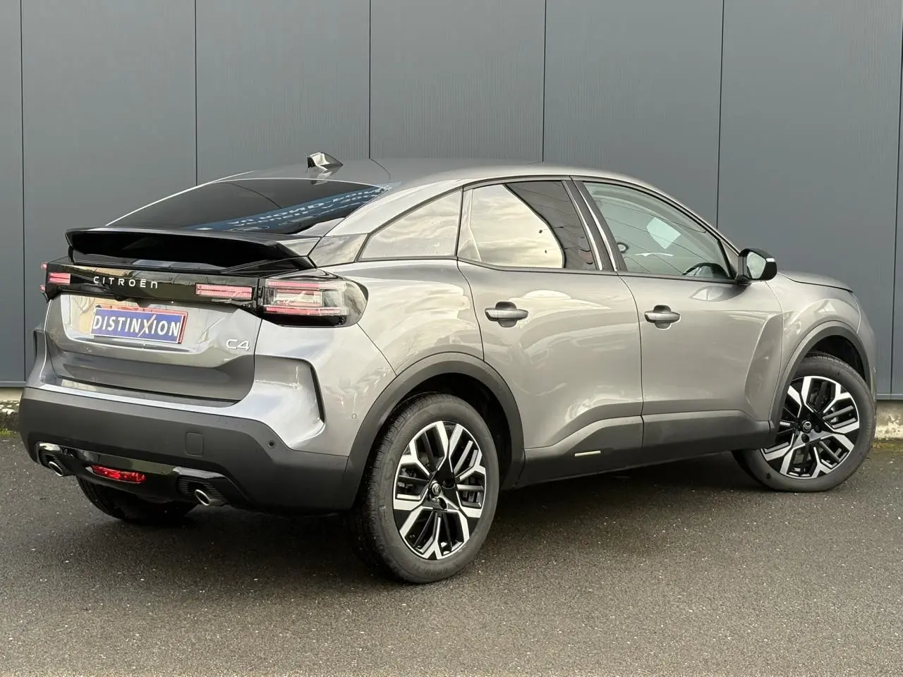 Vue 3/4 arrière droit d'une Citroën C4 Hybrid 145 gris Mercury avec jantes alliage et toit noir brillant.