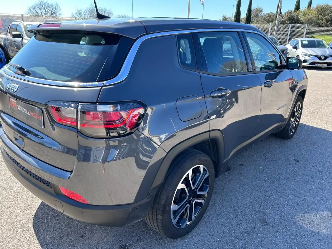 Vue 3/4 arrière droite d'un Jeep Compass gris 2024 avec jantes alliage 18 pouces et feux arrière LED.