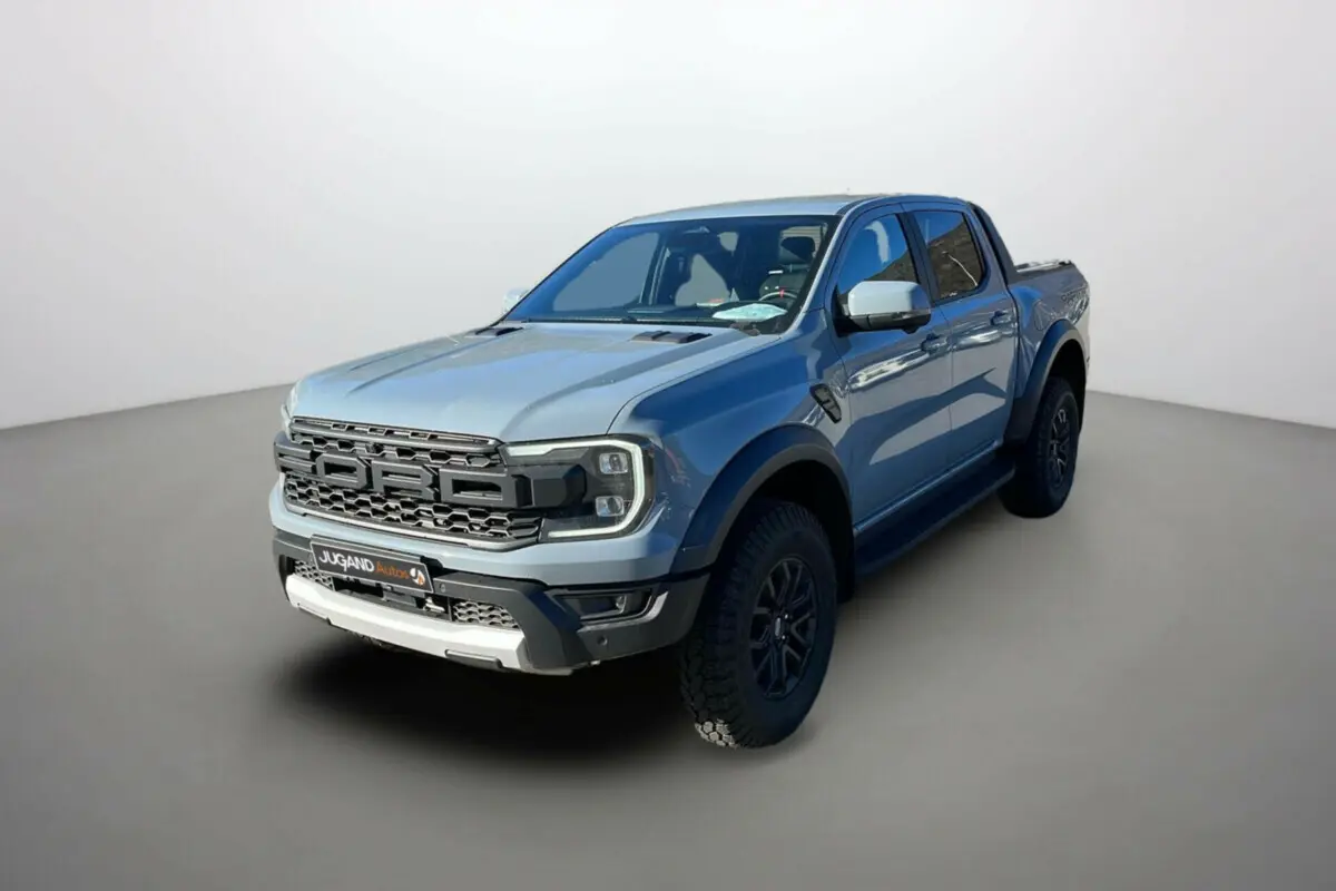 Ford Ranger Raptor gris commandeur en 3/4 avant droit, avec calandre imposante et jantes noires tout-terrain.