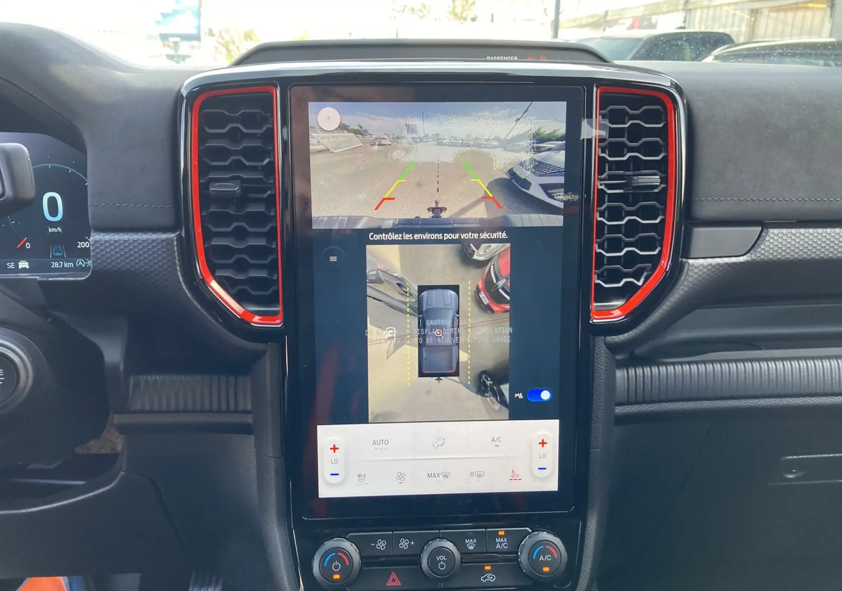 Vue intérieure centrée sur l’écran tactile 12 pouces du Ford Ranger Raptor gris, avec affichage caméra 360° et commandes climatisation.