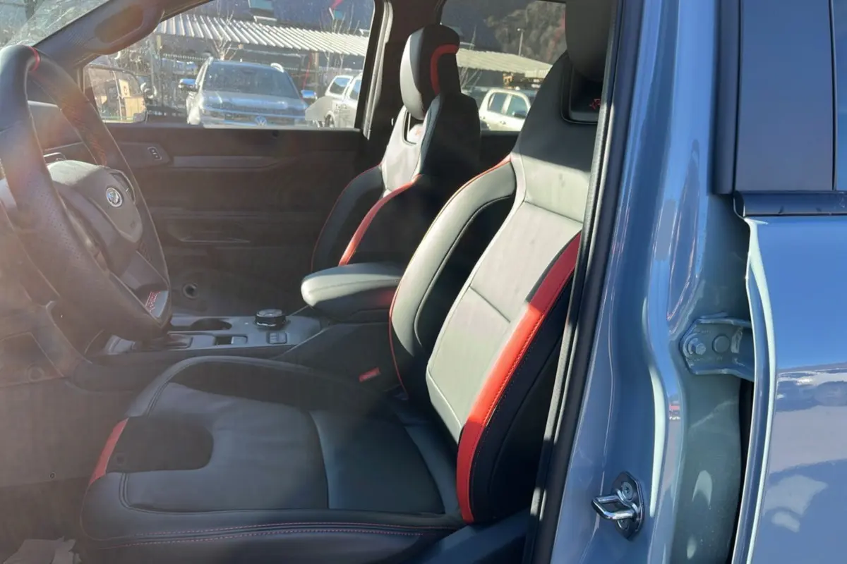 Vue intérieure côté gauche sur les sièges avant cuir noir et rouge du Ford Ranger Raptor gris commandeur 2026.