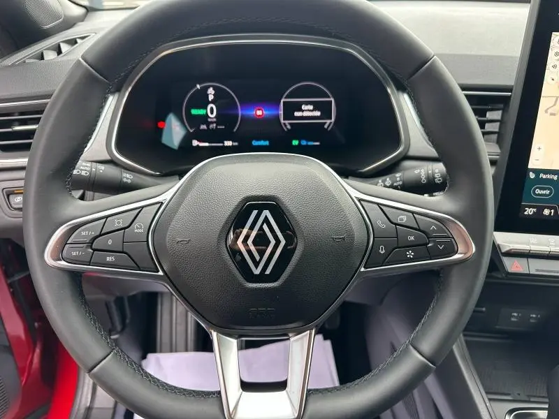 Vue rapprochée du volant multifonction noir du Renault Captur rouge 2025 avec tableau de bord numérique et écran tactile.
