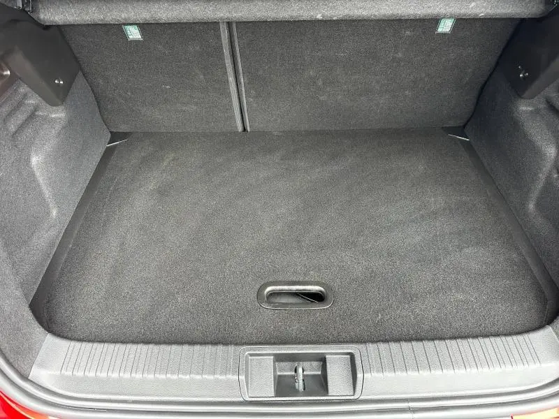 Coffre ouvert vu de dessus du Renault Captur rouge, montrant un espace de chargement propre et tapis gris foncé.