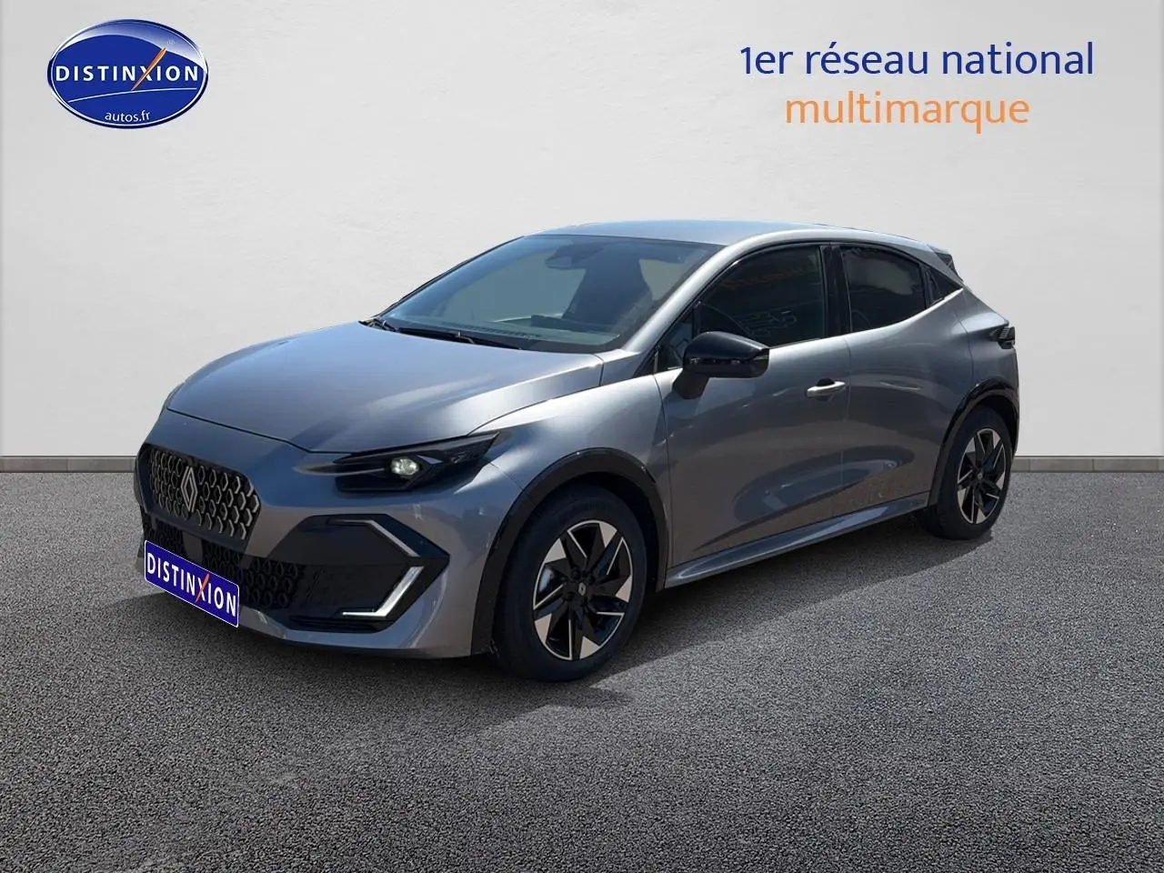 Renault Clio VI gris schiste en 3/4 avant droit, avec jantes alliage et phares LED allumés.