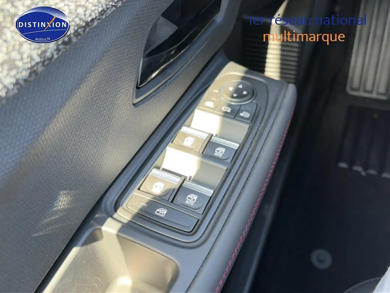 Gros plan sur la commande des vitres électriques côté gauche de la Renault Clio VI, avec surpiqûres rouges visibles.