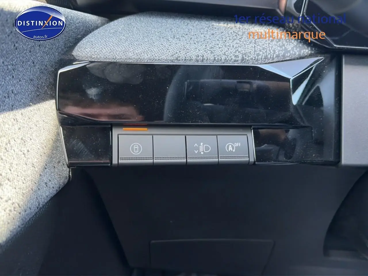 Gros plan sur les commandes de réglage des phares et verrouillage, intérieur noir de la Renault Clio VI gris schiste.
