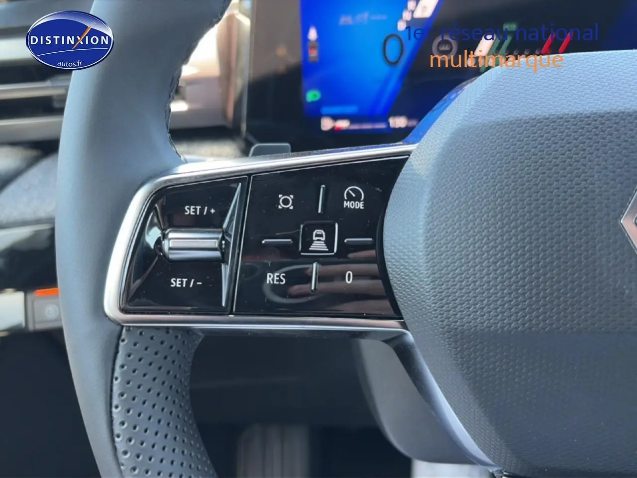Gros plan sur les commandes gauche du volant gris d’une Renault Clio VI avec affichage numérique en arrière-plan.