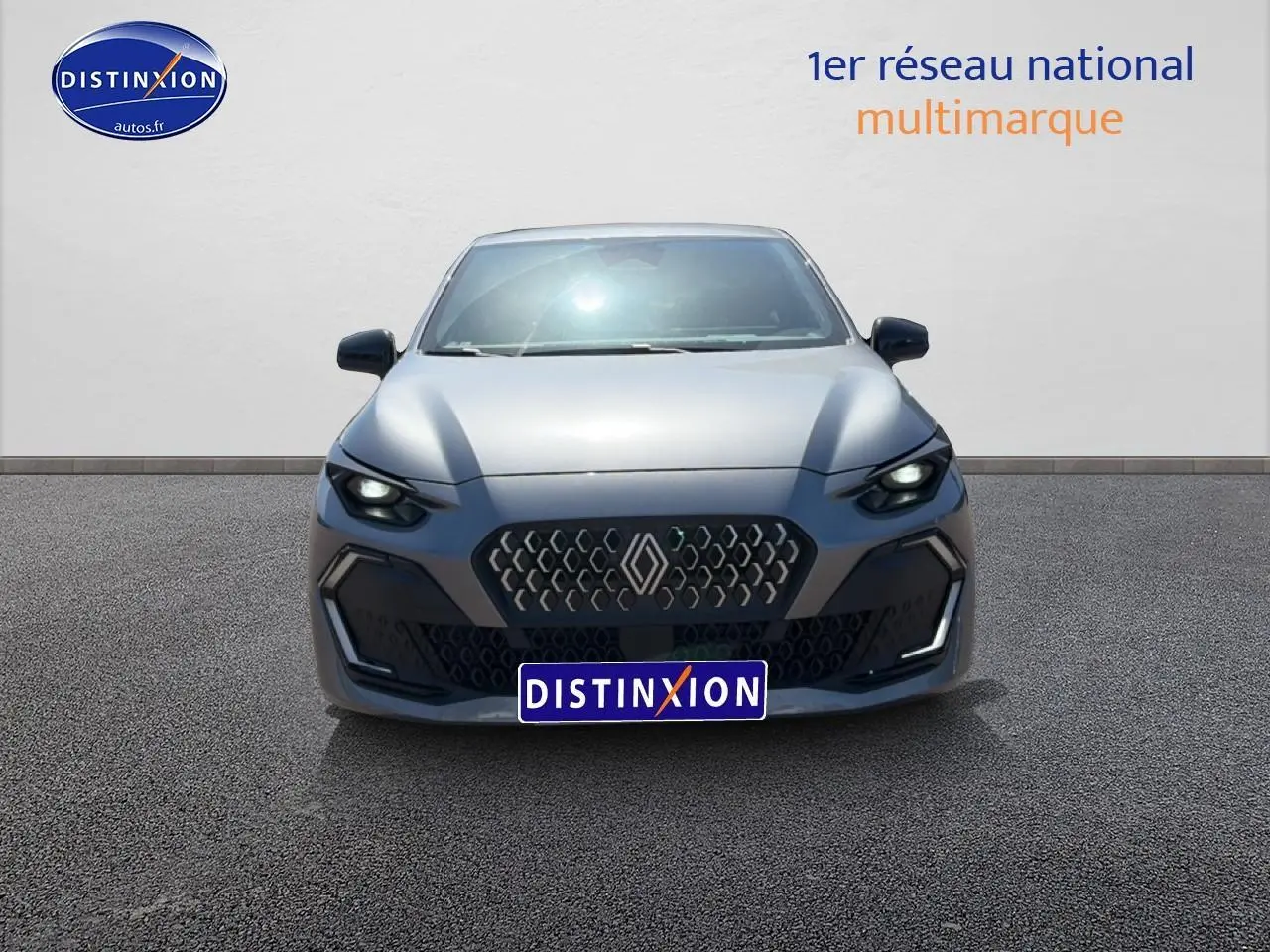 Vue frontale d'une Renault Clio VI gris schiste avec calandre hexagonale et phares LED allumés.