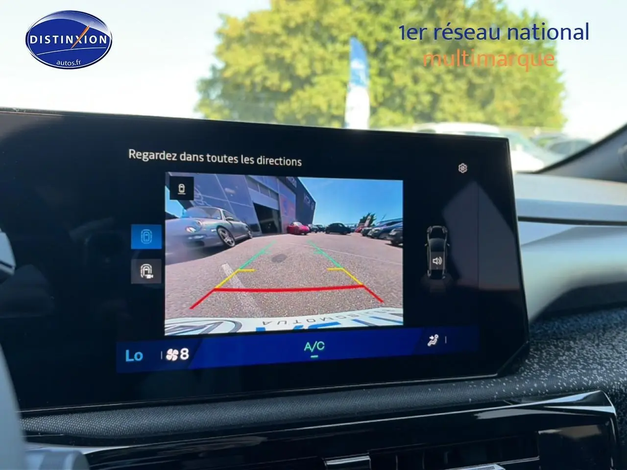 Vue intérieure sur l'écran multimédia affichant la caméra de recul d'une Renault Clio VI gris schiste en stationnement.