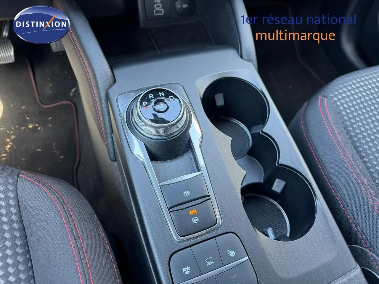 Vue rapprochée de la console centrale du Ford Kuga gris magnétique, mettant en valeur la molette de boîte automatique et les porte-gobelets.