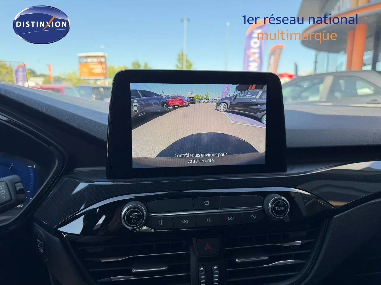 Vue intérieure du tableau de bord du Ford Kuga 2024 avec écran central affichant la caméra de recul, ambiance noire et finitions brillantes.