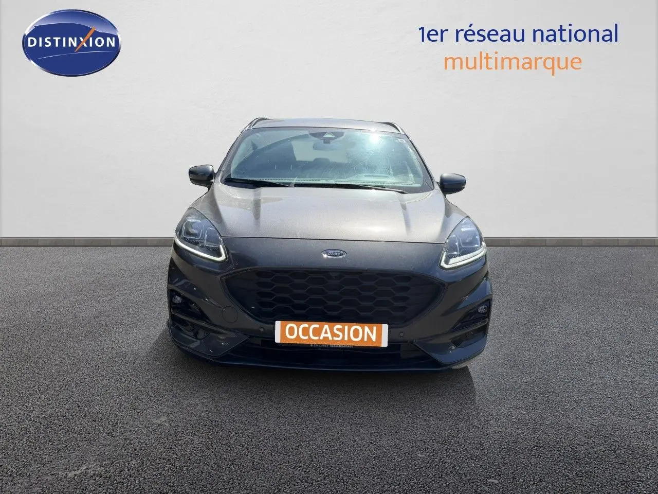 Vue frontale d’un Ford Kuga gris magnétique métal 2024 avec calandre noire et phares LED allumés.