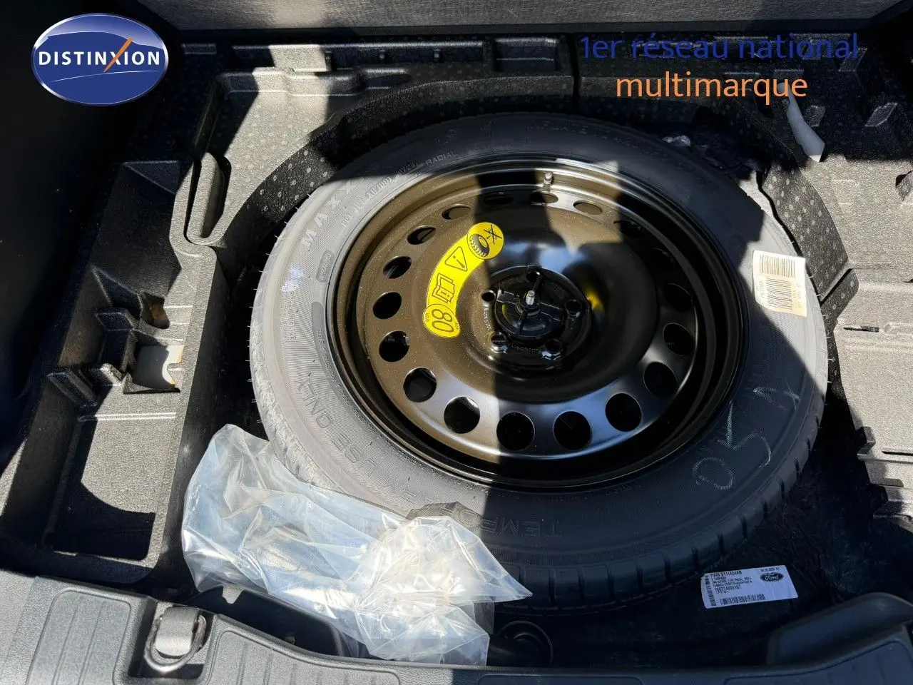 Vue rapprochée de la roue de secours noire dans le coffre du Ford Kuga 2024 gris magnétique métal.