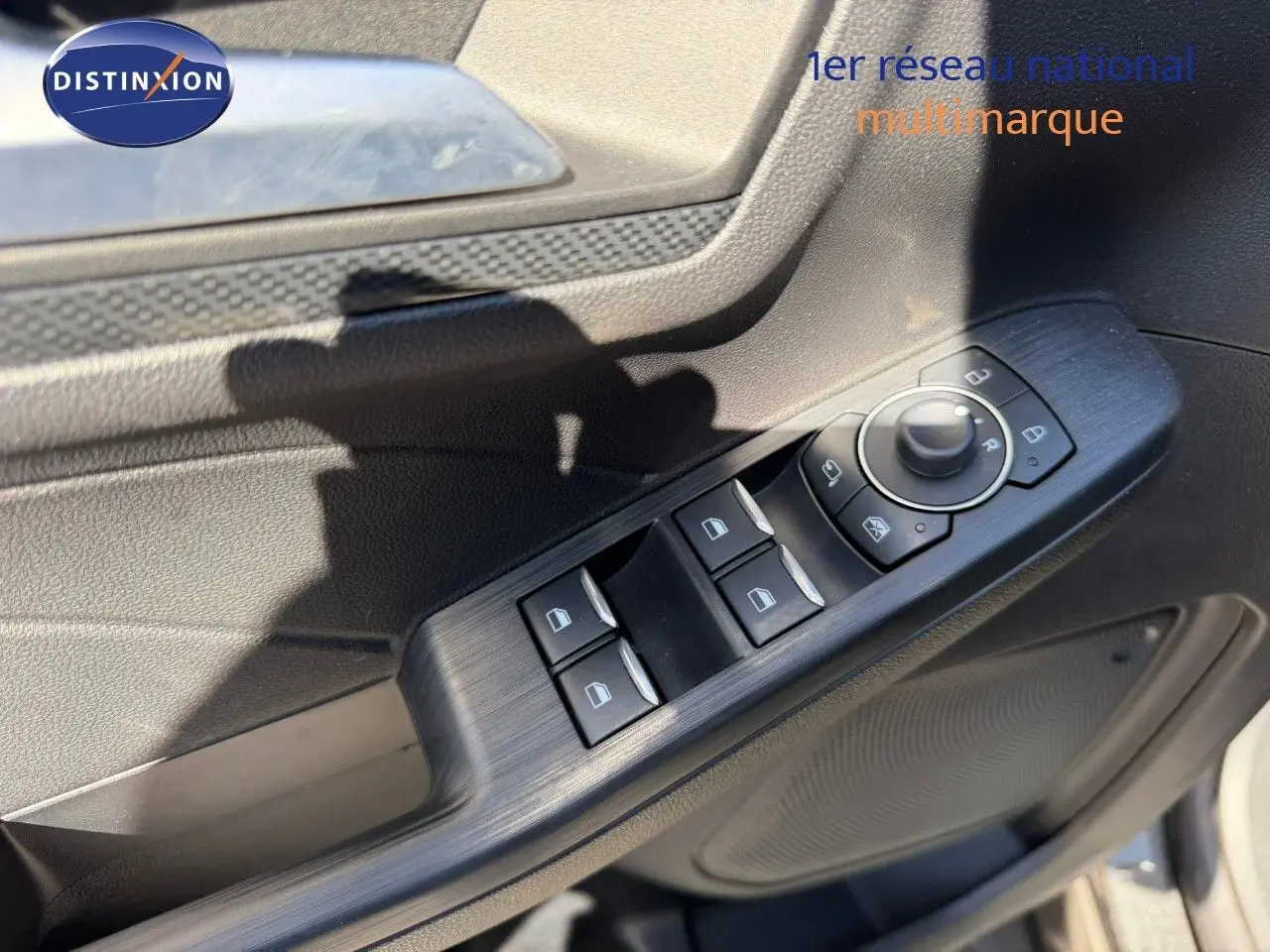 Détail des commandes de lève-vitres et rétroviseurs sur la portière côté gauche d’un Ford Kuga gris magnétique 2024.