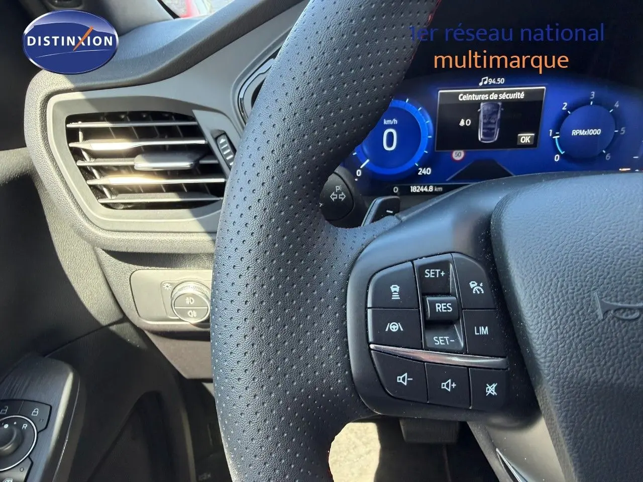 Gros plan sur le volant perforé et le tableau de bord numérique bleu du Ford Kuga 2024, version ST-LINE.