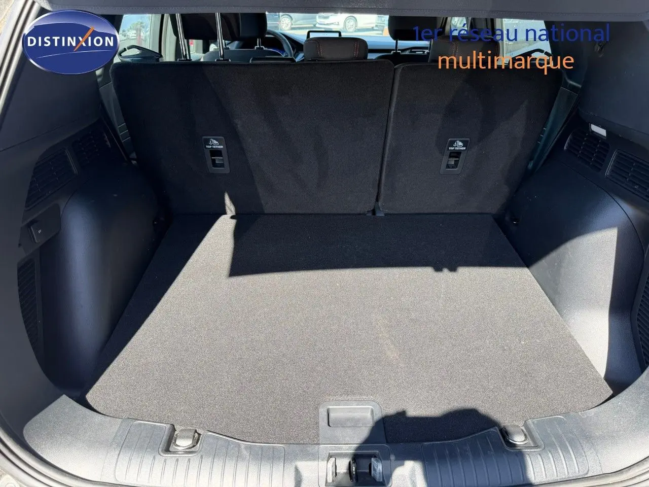 Coffre ouvert du Ford Kuga gris magnétique 2024, vue arrière montrant l’espace de chargement et les dossiers de sièges noirs.