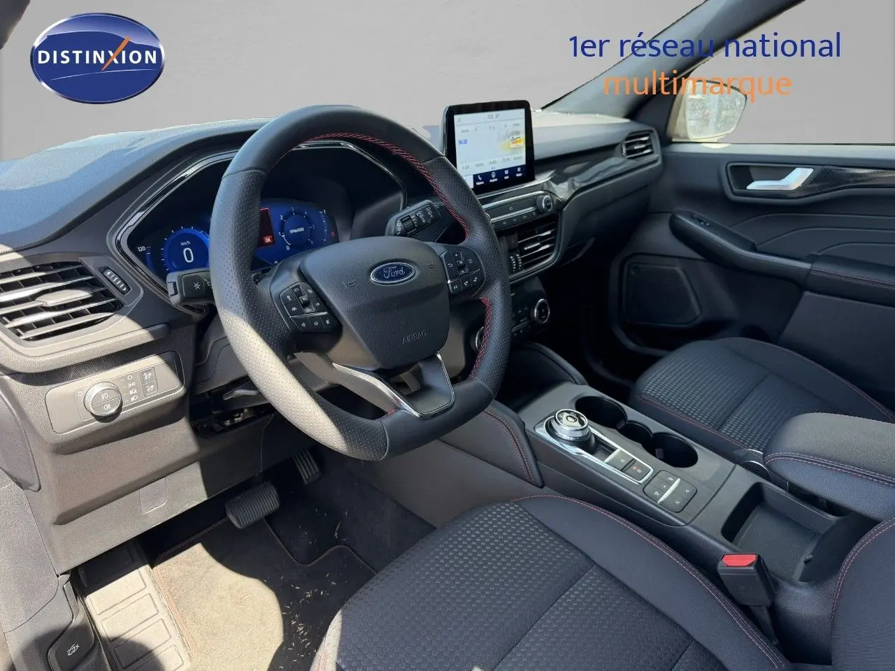 Intérieur avant du Ford Kuga 2024, volant cuir noir avec surpiqûres rouges et écran tactile central visible.