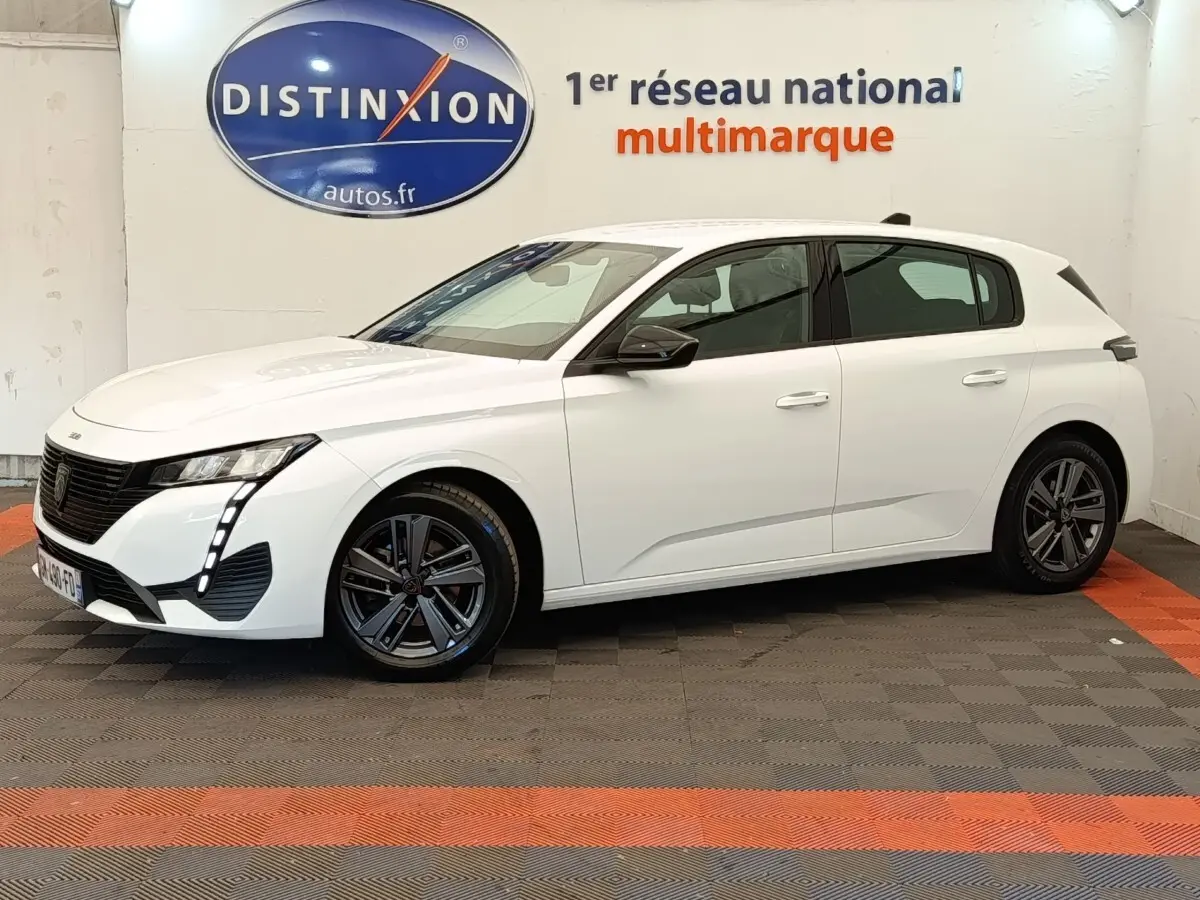 Peugeot 308 blanche vue de profil droit en intérieur, avec feux LED et jantes alliage foncé.