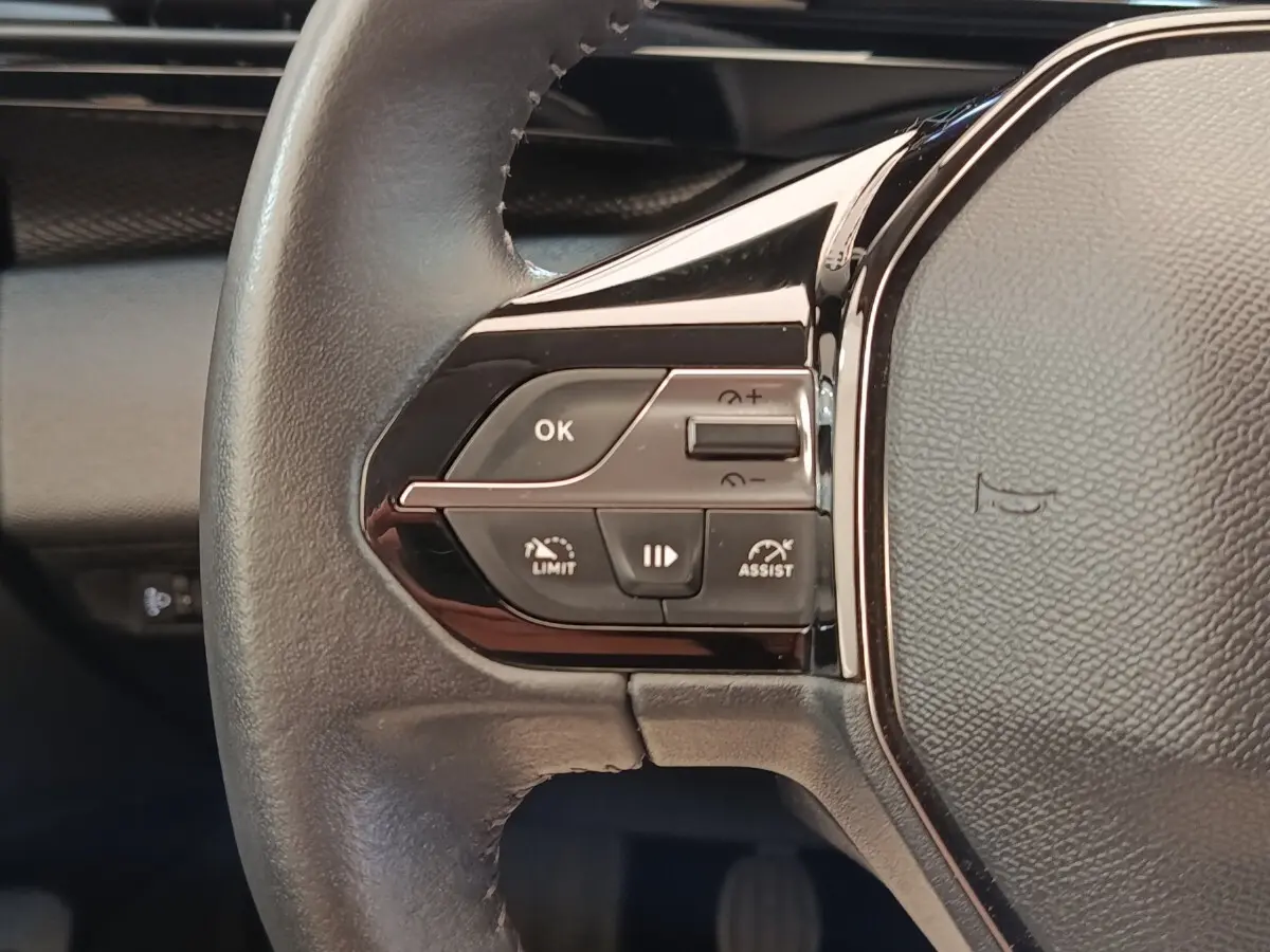Gros plan sur le volant cuir noir de la Peugeot 308 2023 avec commandes multifonctions et régulateur de vitesse.