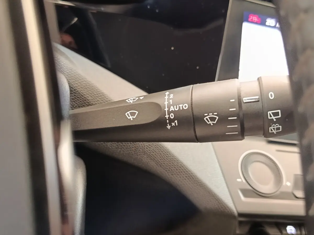 Gros plan sur la commande des essuie-glaces à gauche du volant dans l’habitacle d’une Peugeot 308 blanche.