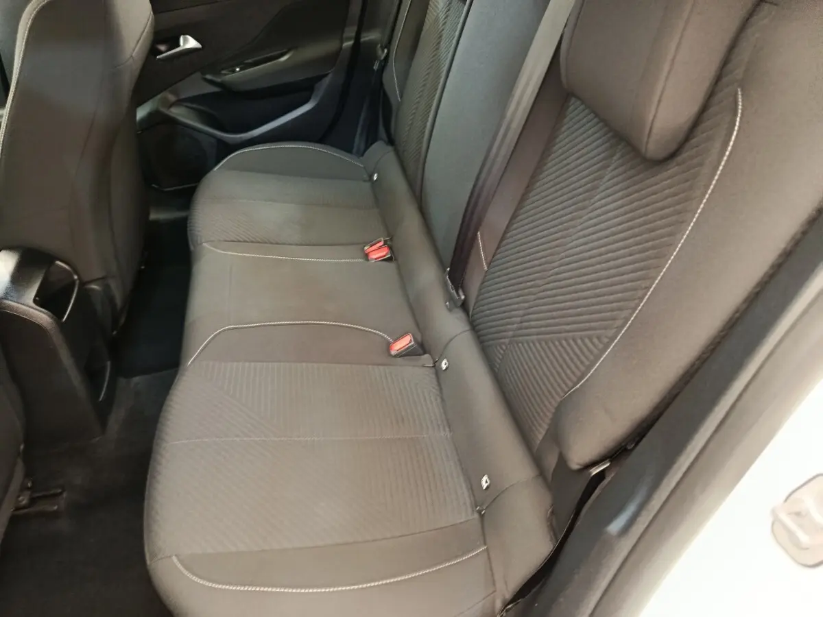 Vue intérieure côté arrière droit montrant la banquette noire avec coutures contrastantes de la Peugeot 308 blanche 2023.