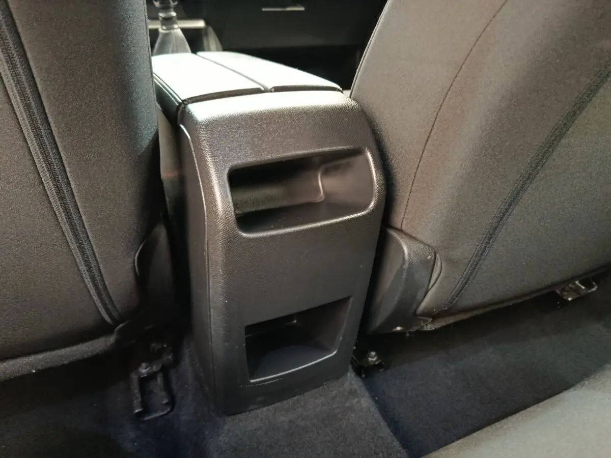 Détail de la console arrière noire entre les sièges arrière gris foncé d'une Peugeot 308 2023.