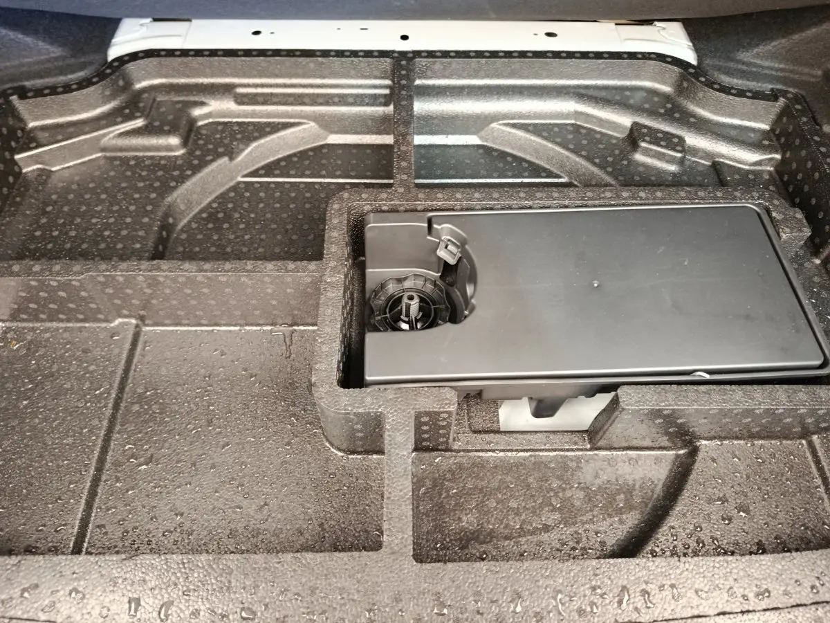Vue rapprochée du compartiment de rangement sous le plancher de coffre de la Peugeot 308 blanche 2023.