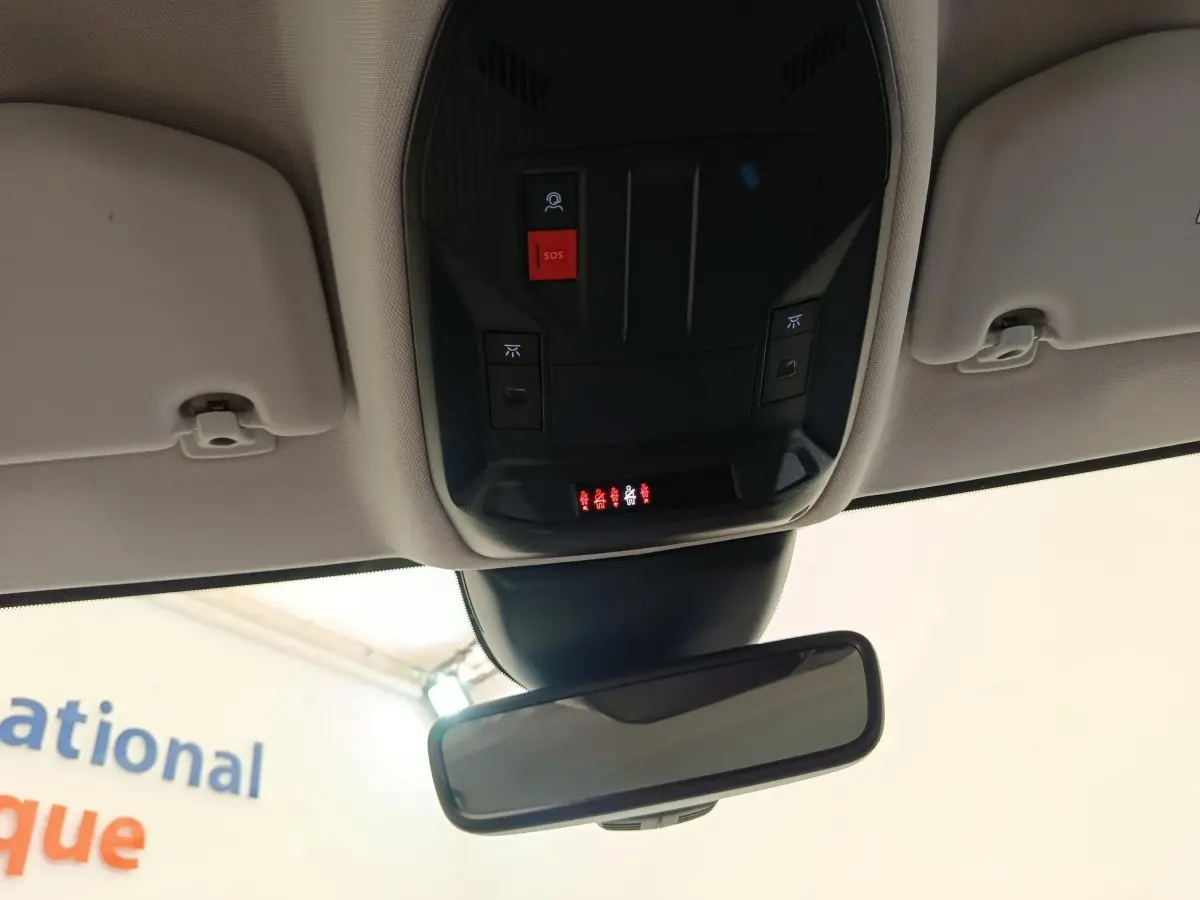 Vue intérieure du plafonnier et rétroviseur intérieur d'une Peugeot 308 blanche de 2023 avec boutons SOS et éclairage intégré.