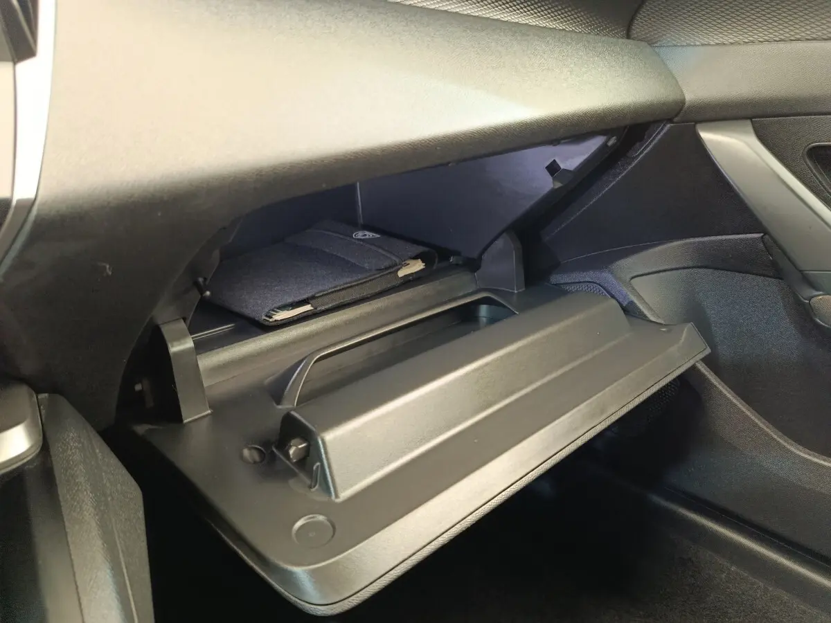 Intérieur de la Peugeot 308 2023, vue sur la boîte à gants ouverte côté passager avec un manuel à l'intérieur.