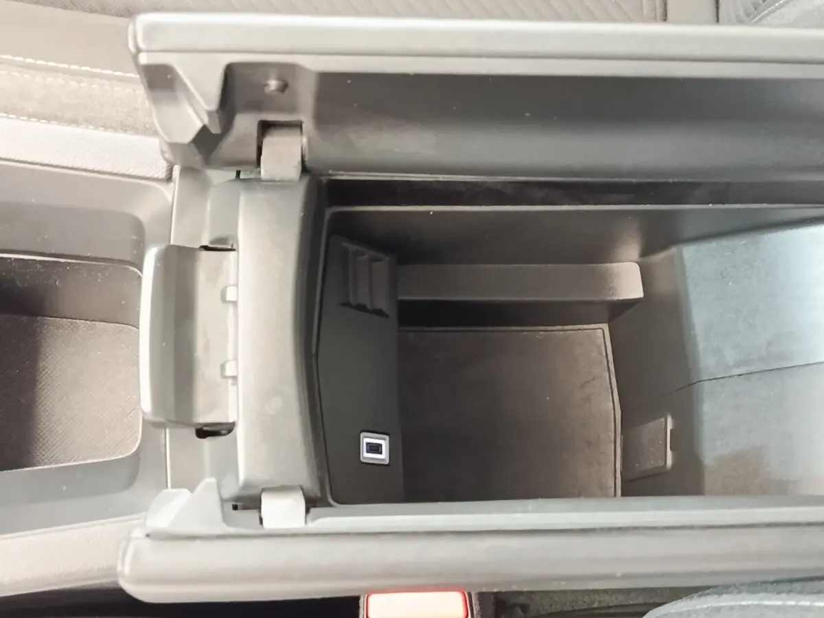 Vue intérieure en plongée du rangement central ouvert de la Peugeot 308 blanche, montrant un port USB intégré.