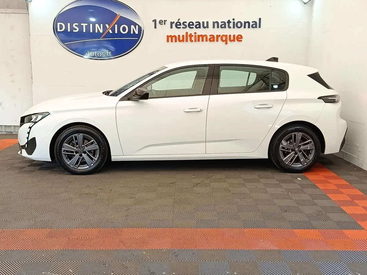 Peugeot 308 blanc vue de profil côté gauche, avec jantes alliage et feux arrière LED distinctifs.