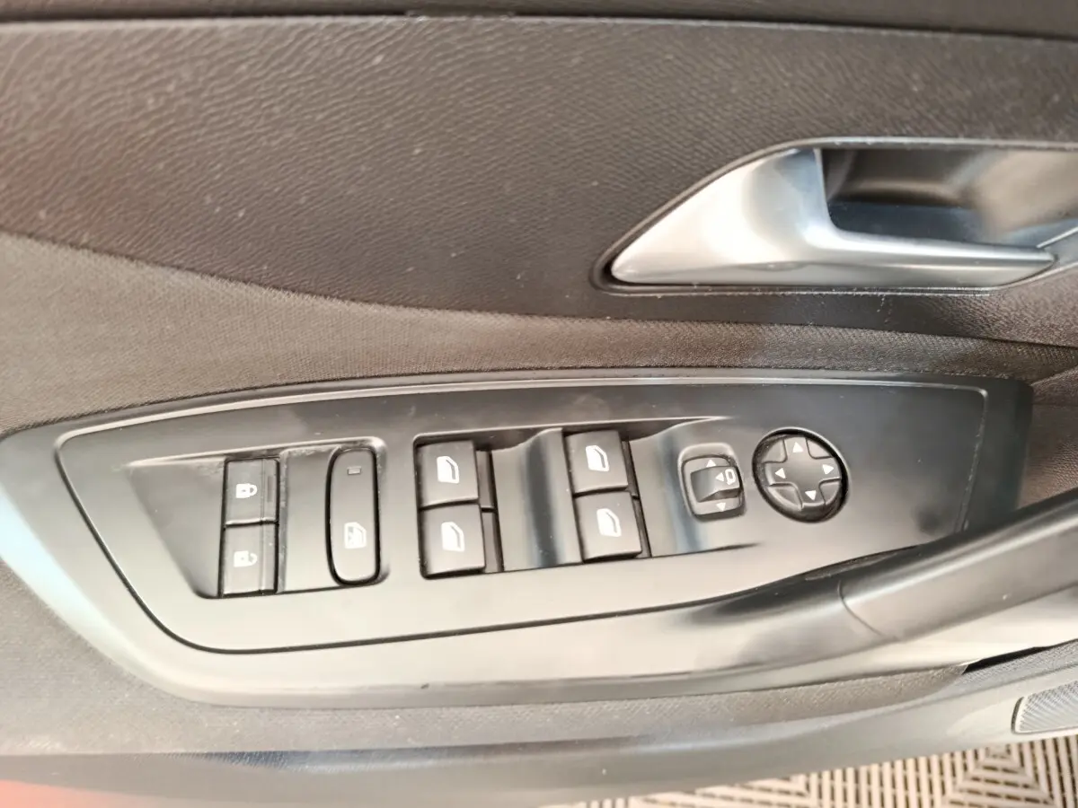 Gros plan sur les commandes de lève-vitres et rétroviseurs côté conducteur d'une Peugeot 308 blanche de 2023.