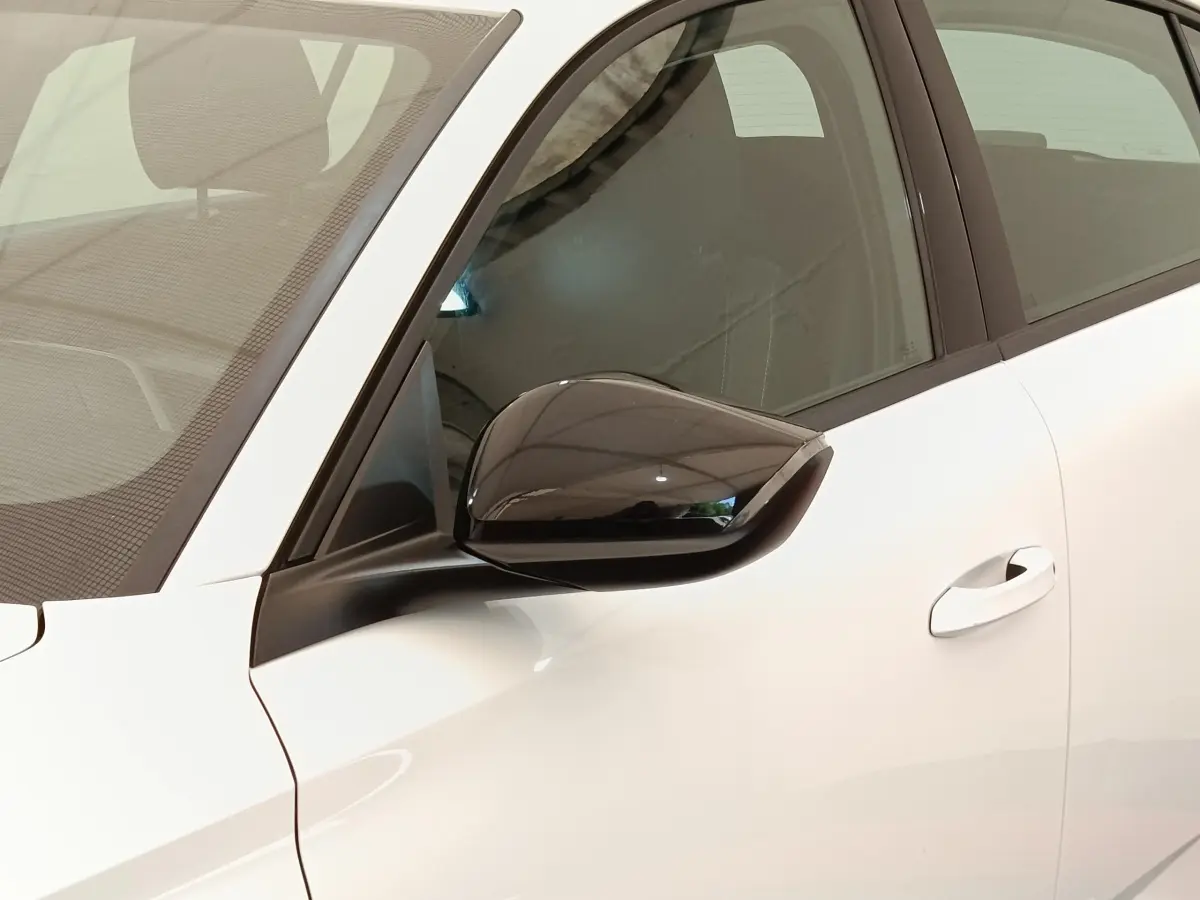 Gros plan sur le rétroviseur noir côté conducteur d'une Peugeot 308 blanche, vue latérale avant gauche.