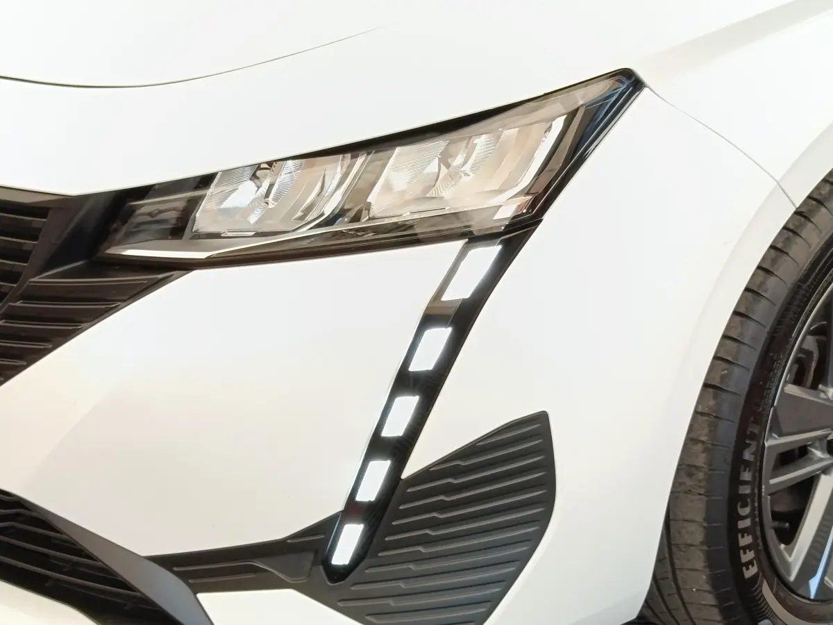 Gros plan sur le phare avant droit blanc de la Peugeot 308 2023 avec feux LED en forme de griffes verticales.