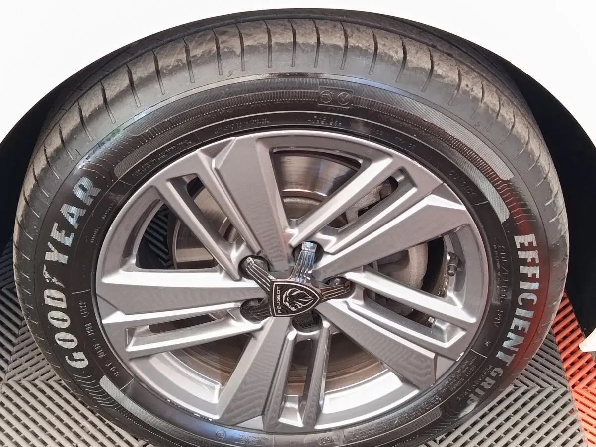 Gros plan sur la roue avant droite d'une Peugeot 308 blanche avec jante alliage et pneu Goodyear Efficient Grip.