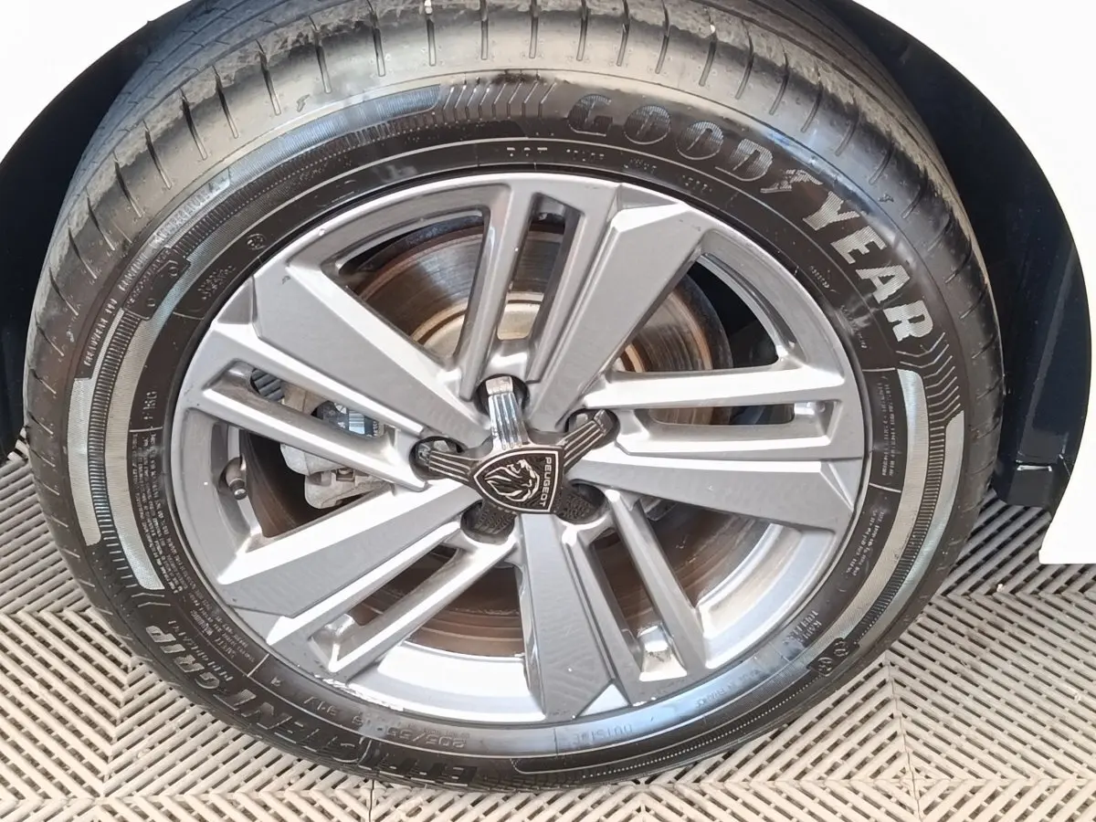 Gros plan sur la roue avant droite de la Peugeot 308 blanche, jante alliage au design moderne et pneu Goodyear.