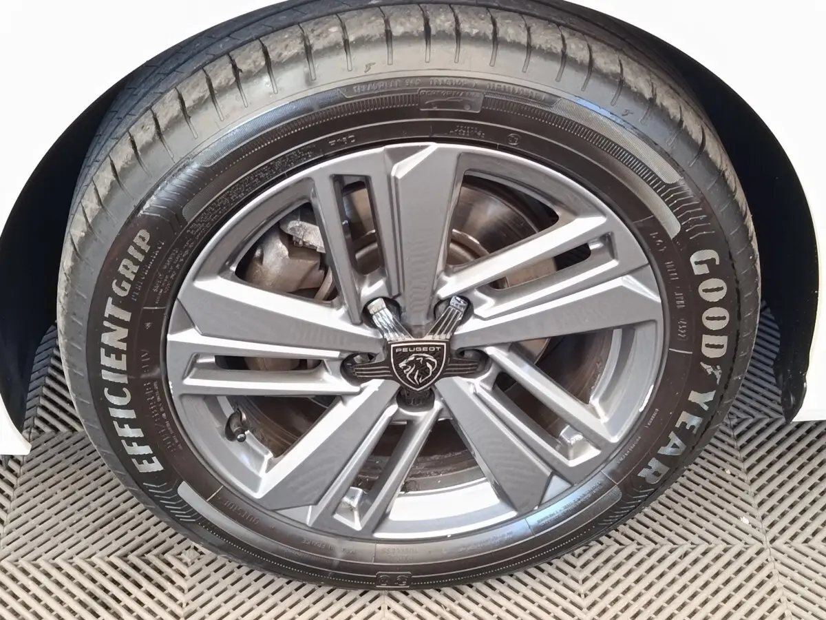 Gros plan sur la roue avant droite d’une Peugeot 308 blanche, avec jante alliage et pneu Goodyear EfficientGrip.